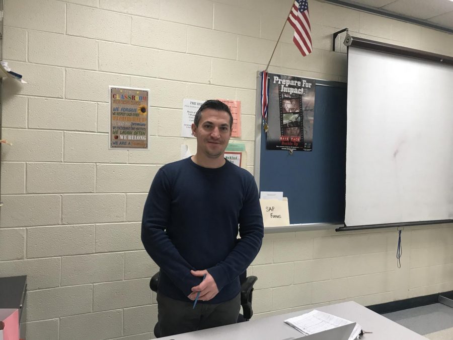 Head Wrestling Coach Brenton Ditchcreek poses by his desk. 